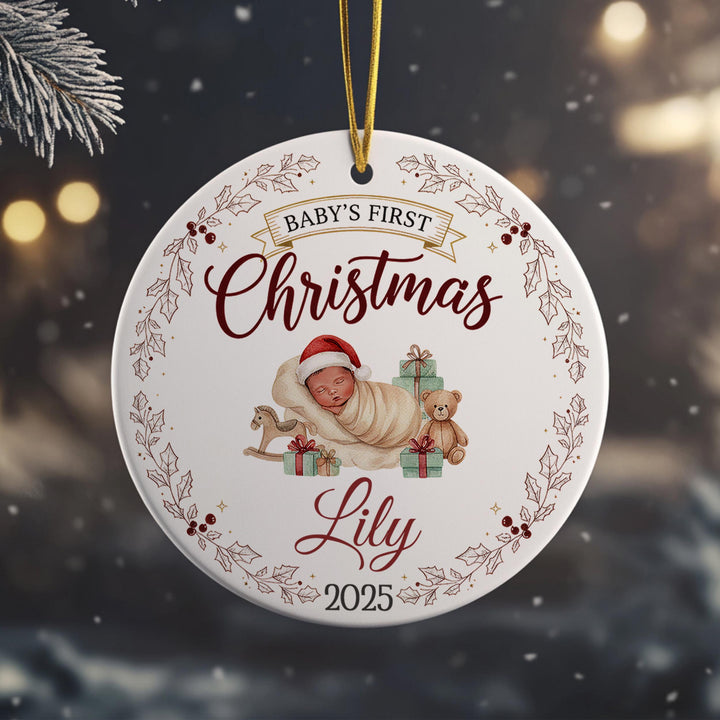 A white ornament with a baby and Christmas-themed decorations hanging from a string.