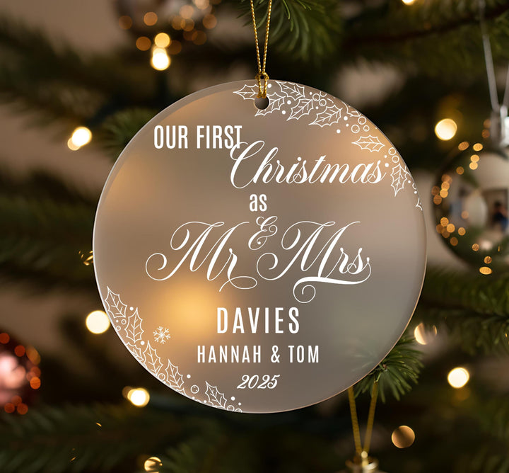 A Christmas ornament with the text &quot;OUR FIRST Christmas as Mr & Mrs DAVIES Hannah & Tom 2025&quot; on it, hanging on a tree.
