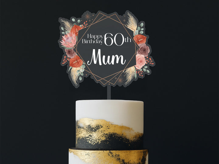 A birthday cake with a floral topper that says &quot;Happy Birthday Mum&quot; in a decorative font.
