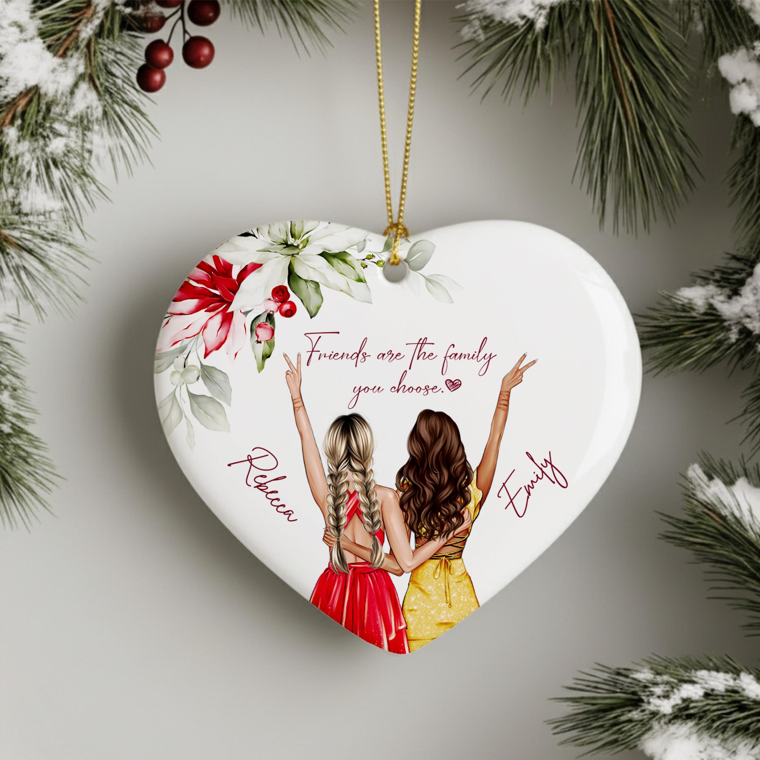 A heart-shaped ornament with two women in colorful dresses, surrounded by flowers and leaves, with the text "Friends are the family you choose" and the names "Rebecca" and "Emilly" written below.