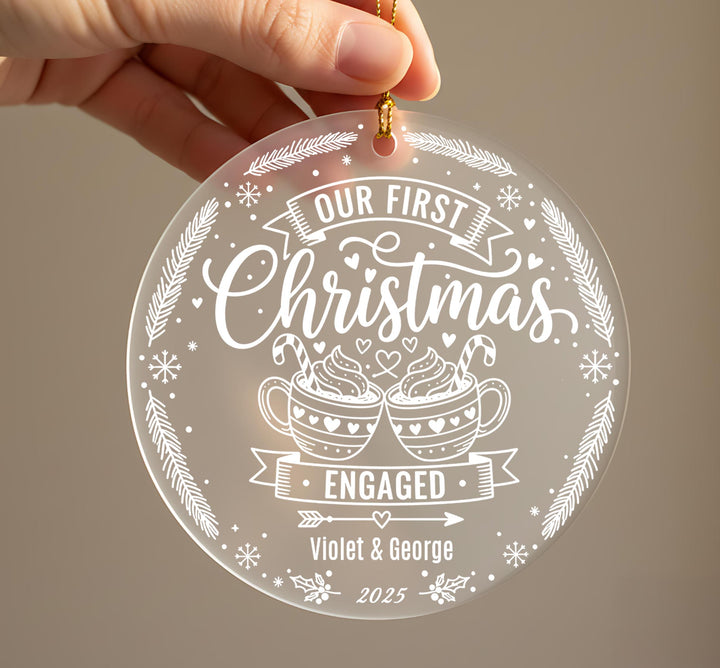 A hand holding a clear ornament with a festive design and text.