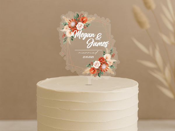 Personalised boho wedding cake topper featuring geometric frame with coral roses, pampas grass and custom names Megan & James married 23.10.2025 on white wedding cake