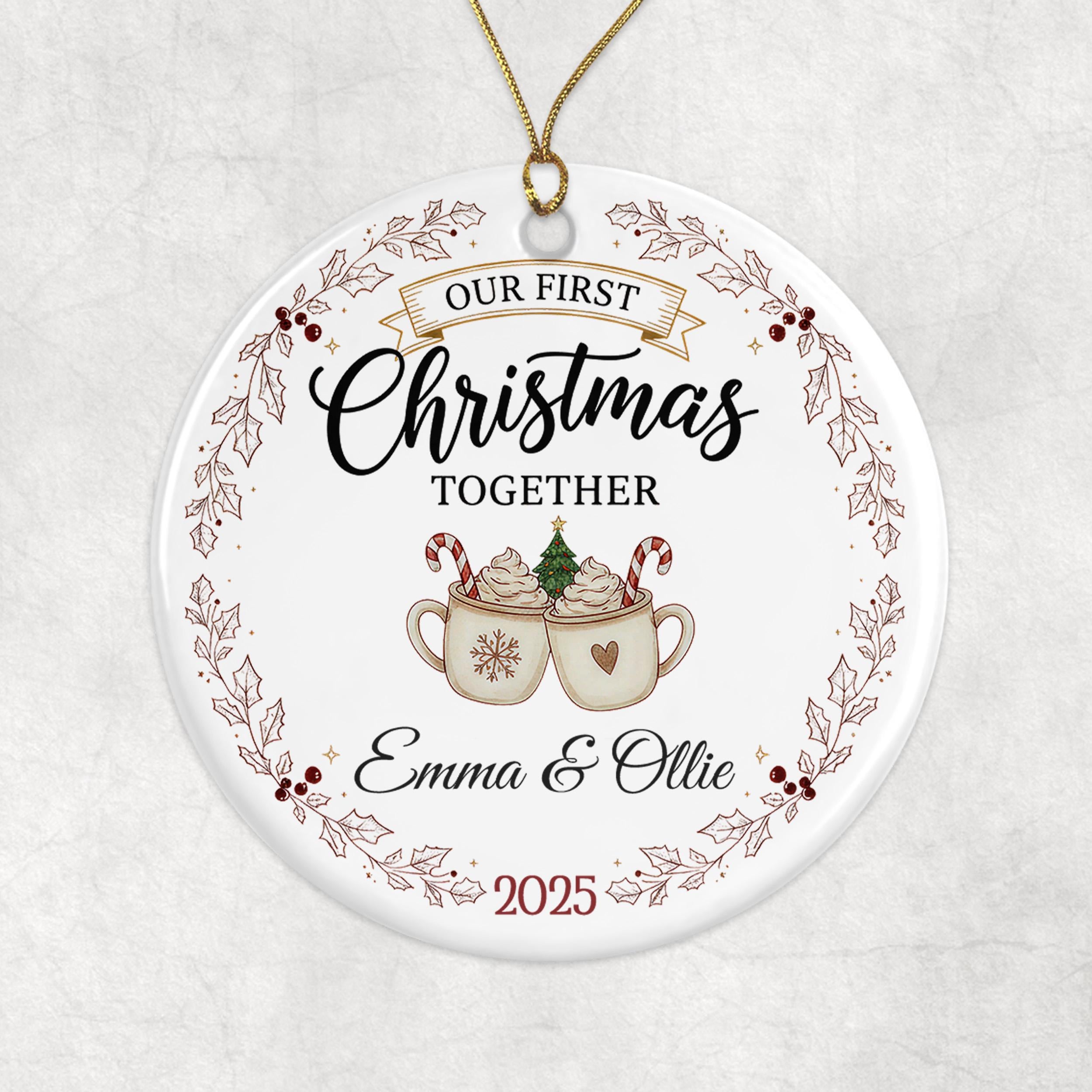 A white ornament with a festive design, featuring a couple enjoying hot chocolate together. The text on the ornament reads "Our first Christmas together" and "Emma & Ollie" along with the year "2025".