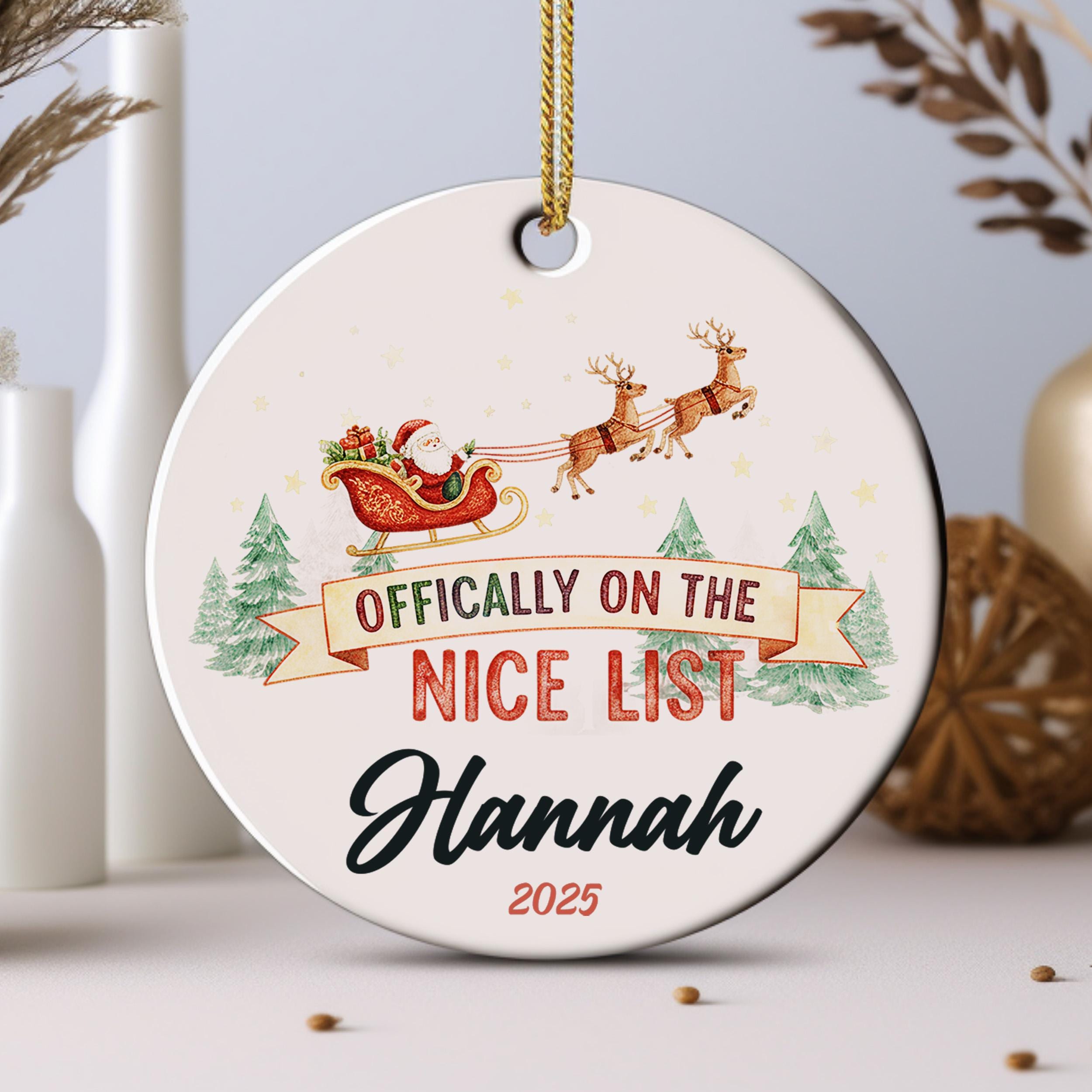 An ornament with a Santa Claus sleigh and reindeer, along with the text " Officially on the NICE LIST Hannah" and the year "2025".