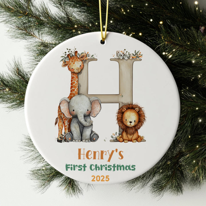 A white ornament with a giraffe, elephant, and lion, along with the text &quot;Henry&#39;s First Christmas 2025&quot;.
