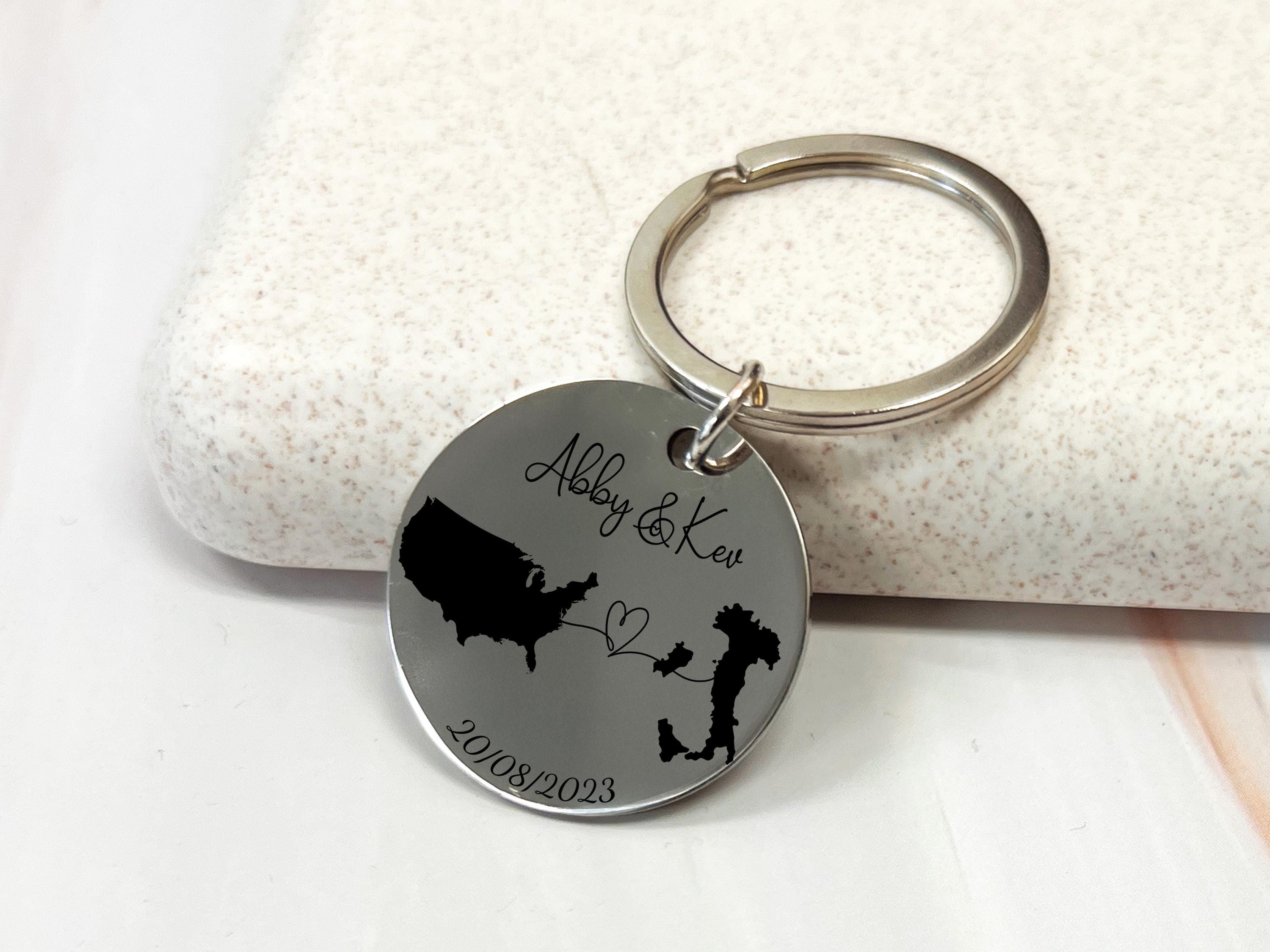 Personalised country map keychain with two engraved countries, names, connecting heart, and date, custom long distance relationship gift.