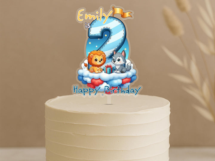A birthday cake with a cartoon animal topper, specifically a lion and a dog, celebrating Emily's 2nd birthday.