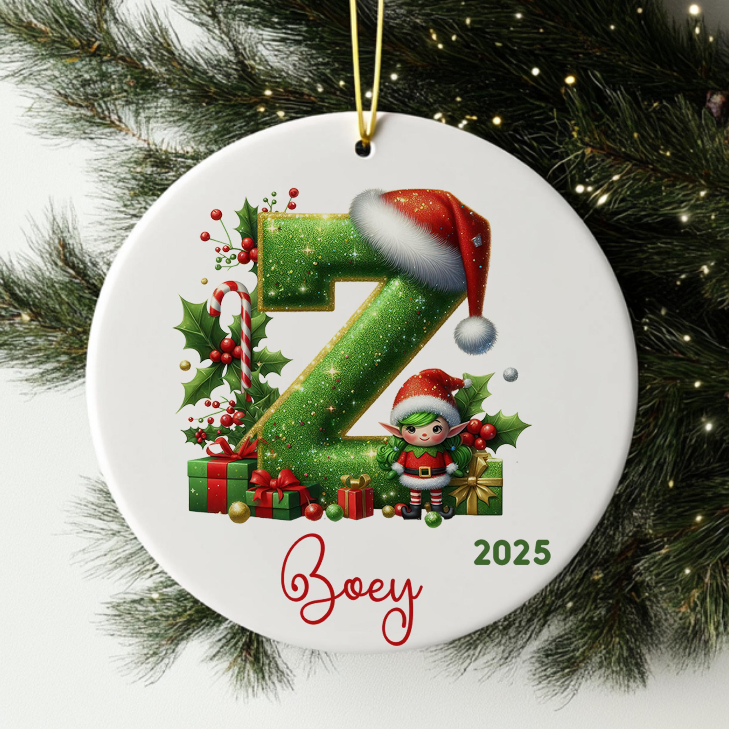A white ornament with a green glittery letter "Z" and a small elf wearing a Santa hat, surrounded by Christmas decorations such as presents and berries.