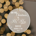 Personalised first Christmas as Mr and Mrs frosted acrylic ornament hanging with gold ribbon showing elegant engraved text Our First Christmas as Mr & Mrs, surname Davies, names Hannah and Tom 2025, decorated with holly leaves, berries and snowflakes against bokeh lightsRetry