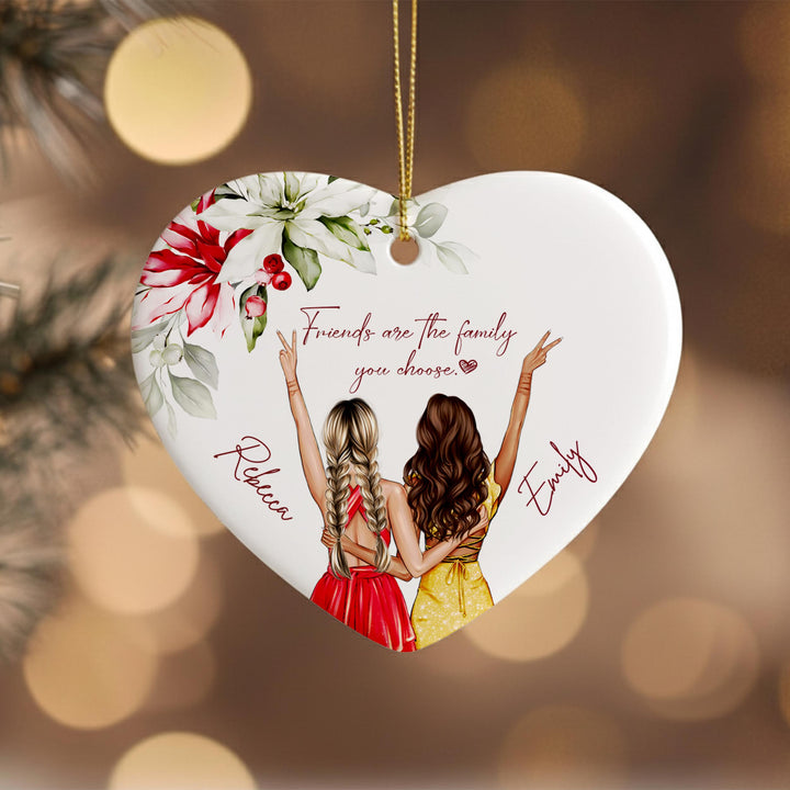 A heart-shaped ornament with two women in a loving embrace, surrounded by flowers and the text &quot;Friends are the family you choose.&quot;