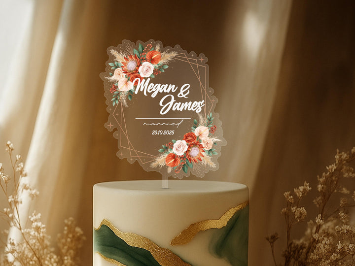 A wedding cake topper with a floral design and the names &quot;Megan & James&quot; written on it.