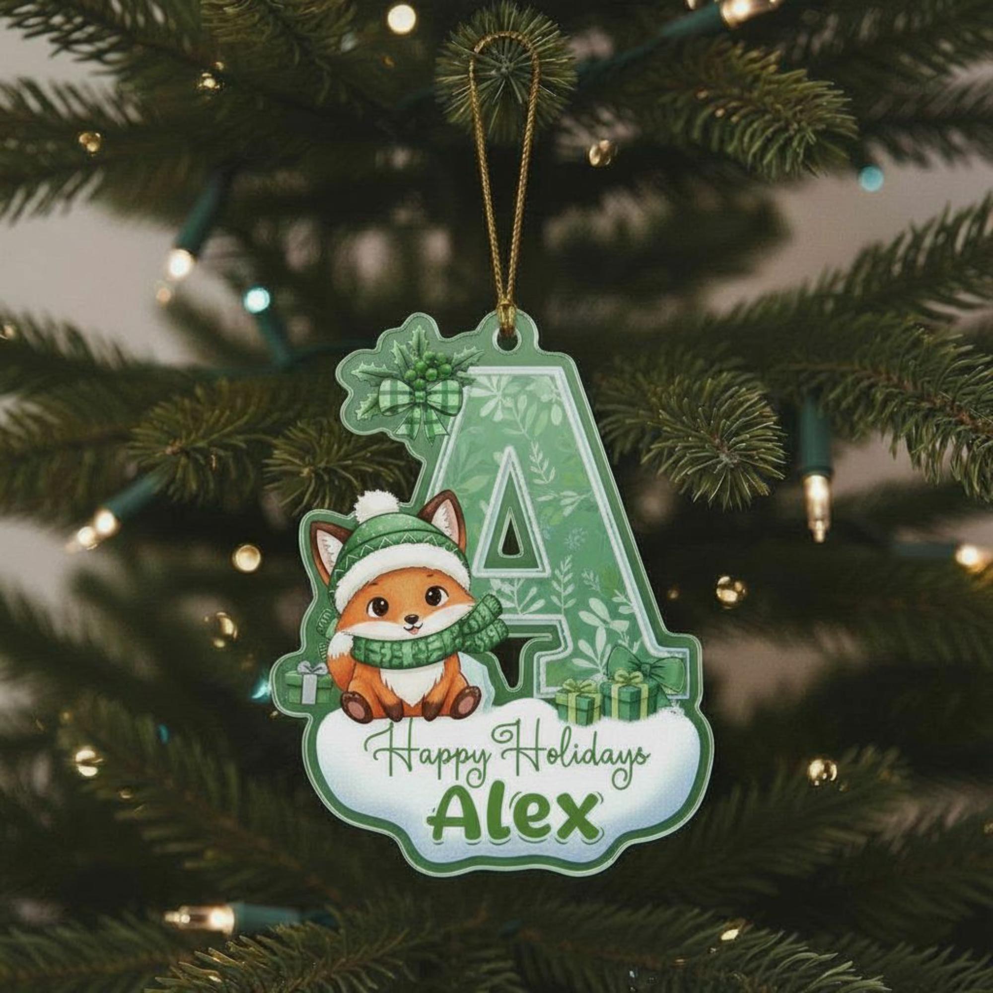 A green ornament with a cartoon fox wearing a scarf and hat, sitting on a white base with the text "Happy Holidays Alex" written on it.