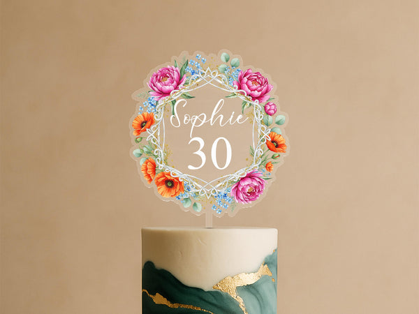 Personalised celebration cake topper featuring geometric frame with pink peonies, orange poppies, blue wildflowers and custom name Sophie 30 on elegant green and gold celebration cake