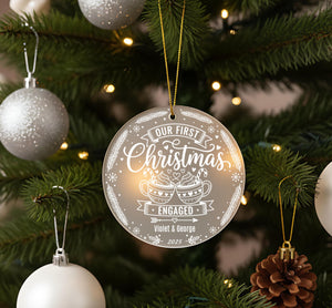 A close-up of a Christmas tree with ornaments, including a large ornament that says "Our first Christmas engaged Violet & George" and smaller ornaments.