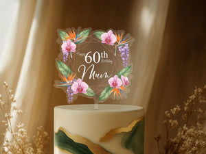 A cake topper with a floral design and the text "Happy 60th Birthday Mum" on it, placed on top of a cake.