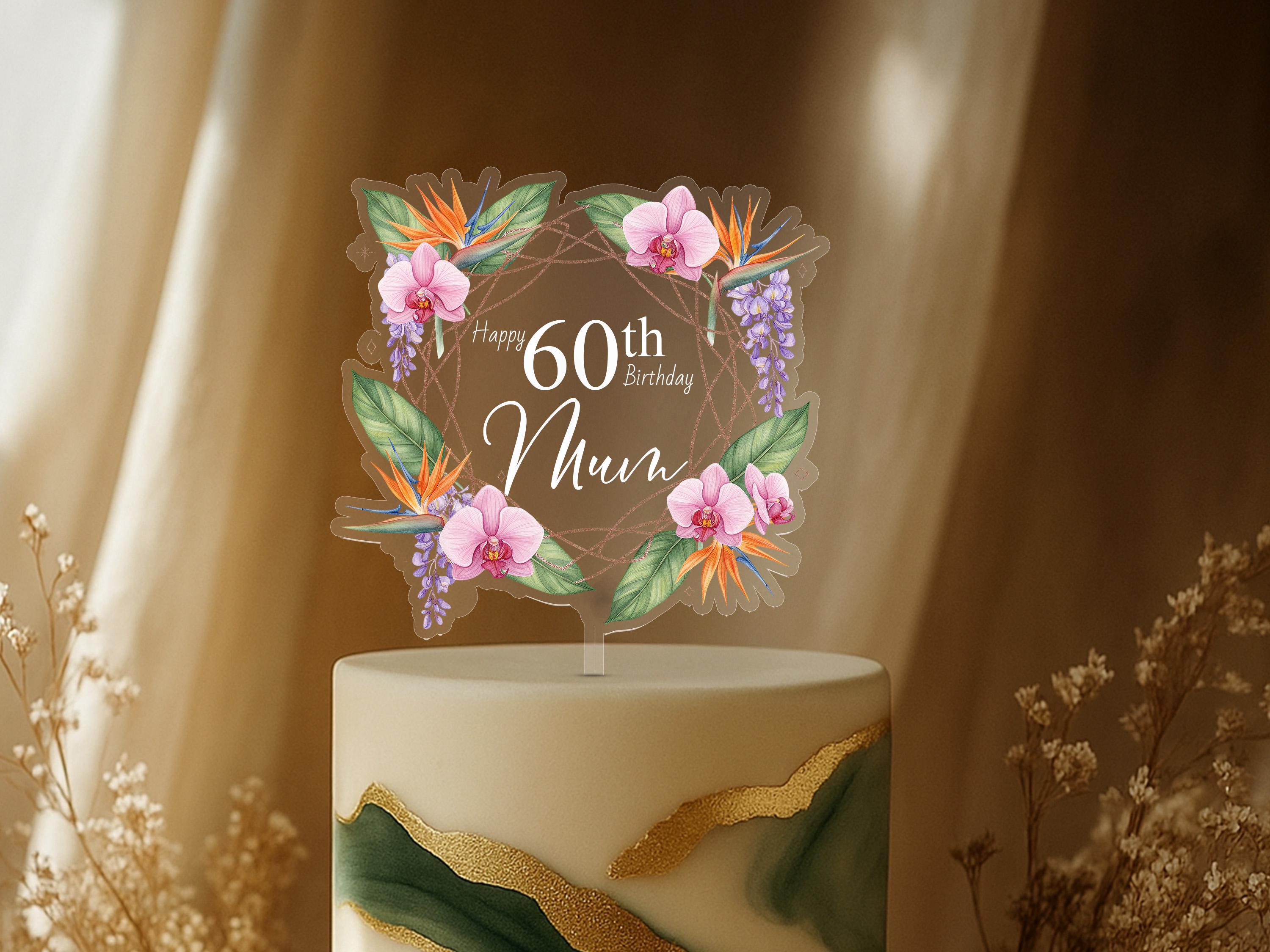 A cake topper with a floral design and the text "Happy 60th Birthday Mum" on it, placed on top of a cake.