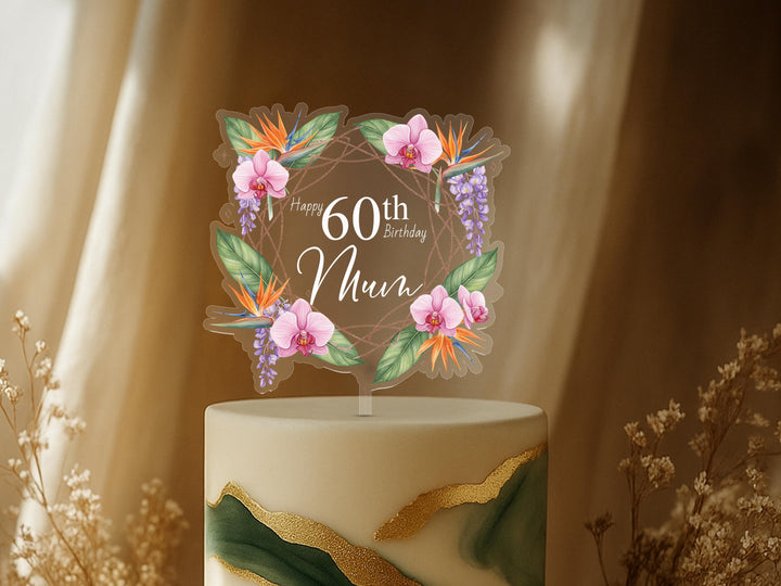 A cake topper with a floral design and the text &quot;Happy 60th Birthday Mum&quot; on it, placed on top of a cake.
