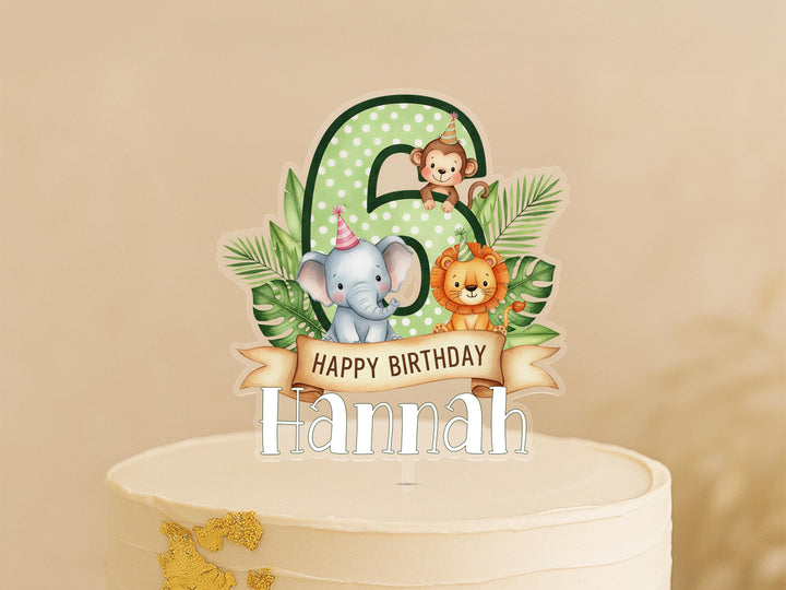 A birthday cake topper with a number 6, featuring a monkey, elephant, and lion surrounded by tropical leaves.