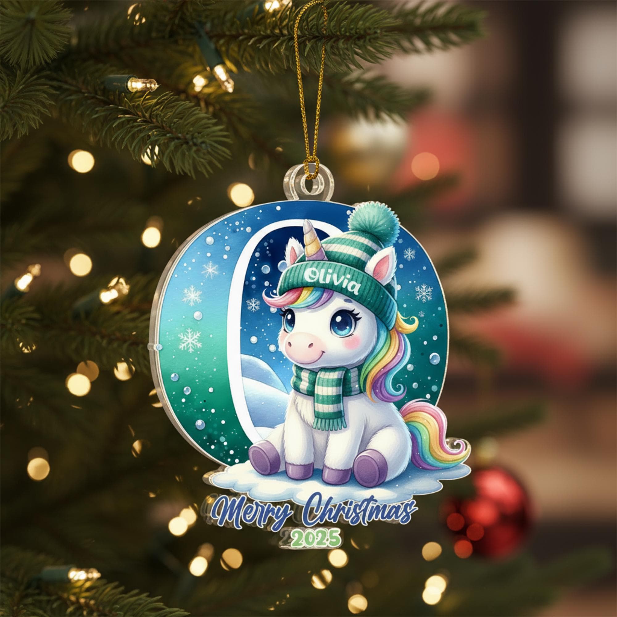 A Christmas ornament featuring a unicorn wearing a green hat and scarf, with the name "Olivia" written on it, hanging on a decorated Christmas tree.