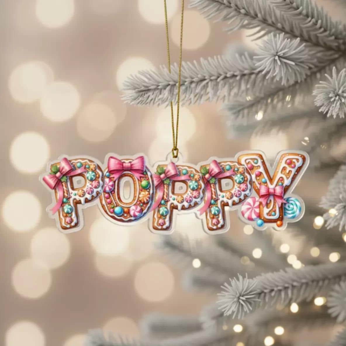 A Personalised gingerbread ornament shaped like the word "POPPY" made of colorful candy and decorations, hanging on a Christmas tree.