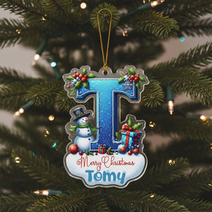 A Christmas ornament shaped like the letter "T" with a snowman, presents, and other holiday decorations.