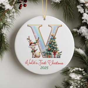 A white ceramic ornament with a large letter "V" and a reindeer, along with a Christmas tree and presents, hangs on a wall.