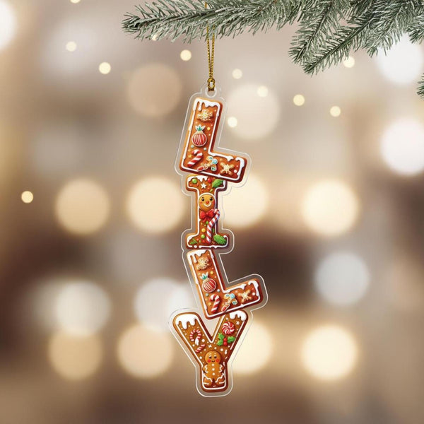Vertical personalised gingerbread name ornament reading “Oliver,” hanging on Christmas tree branch.