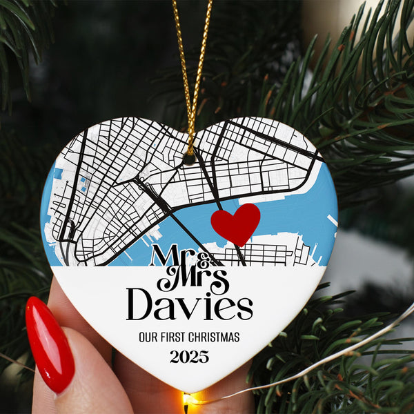 A heart-shaped ornament with a map of a city and a red heart symbol, hanging on a Christmas tree.