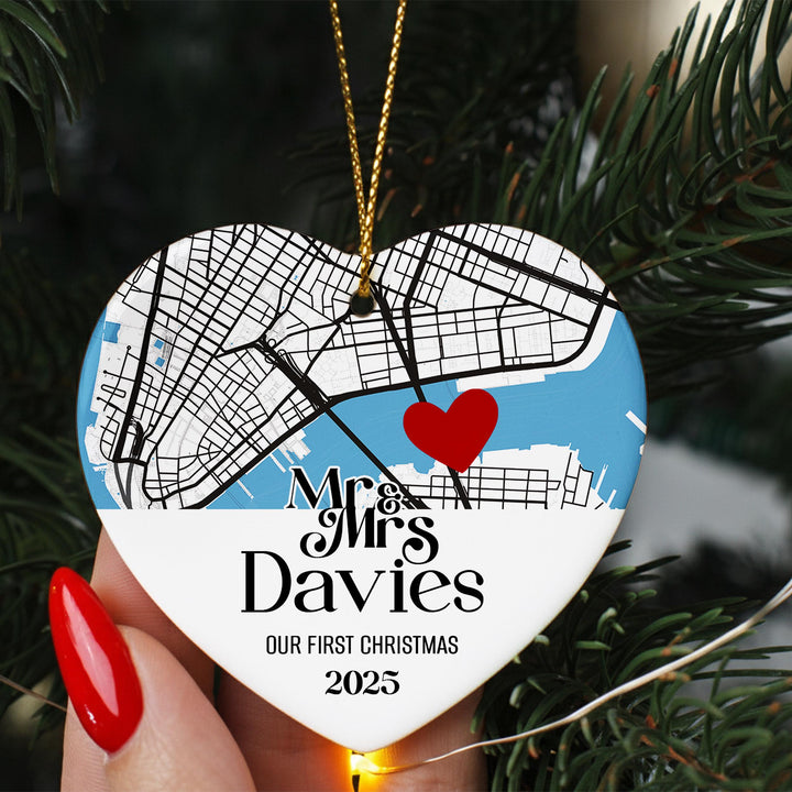 A heart-shaped ornament with a map of a city and a red heart symbol, hanging on a Christmas tree.
