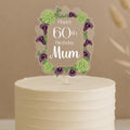 Personalised 60th birthday cake topper featuring elegant oval frame with purple calla lilies, green hydrangeas and custom name Mum on white celebration cake