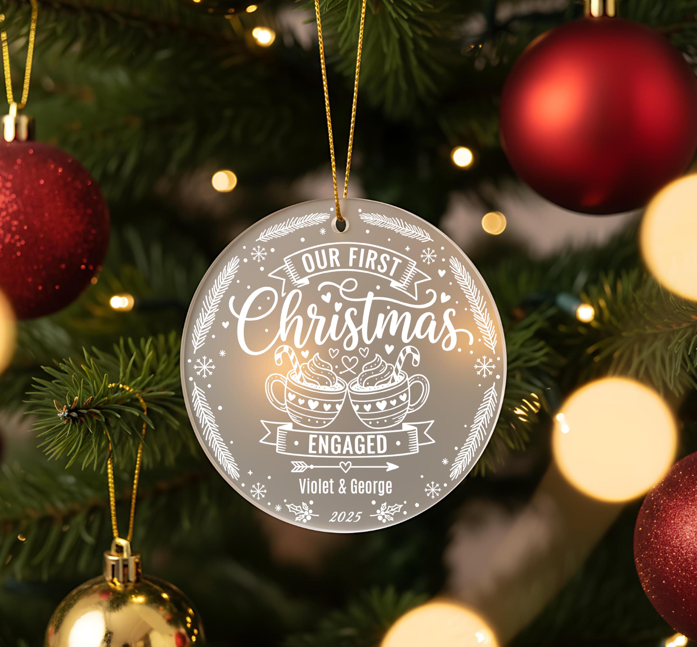 A Christmas tree decorated with ornaments, including a large ornament that says "Our First Christmas Engaged Violet & George" and smaller ornaments.