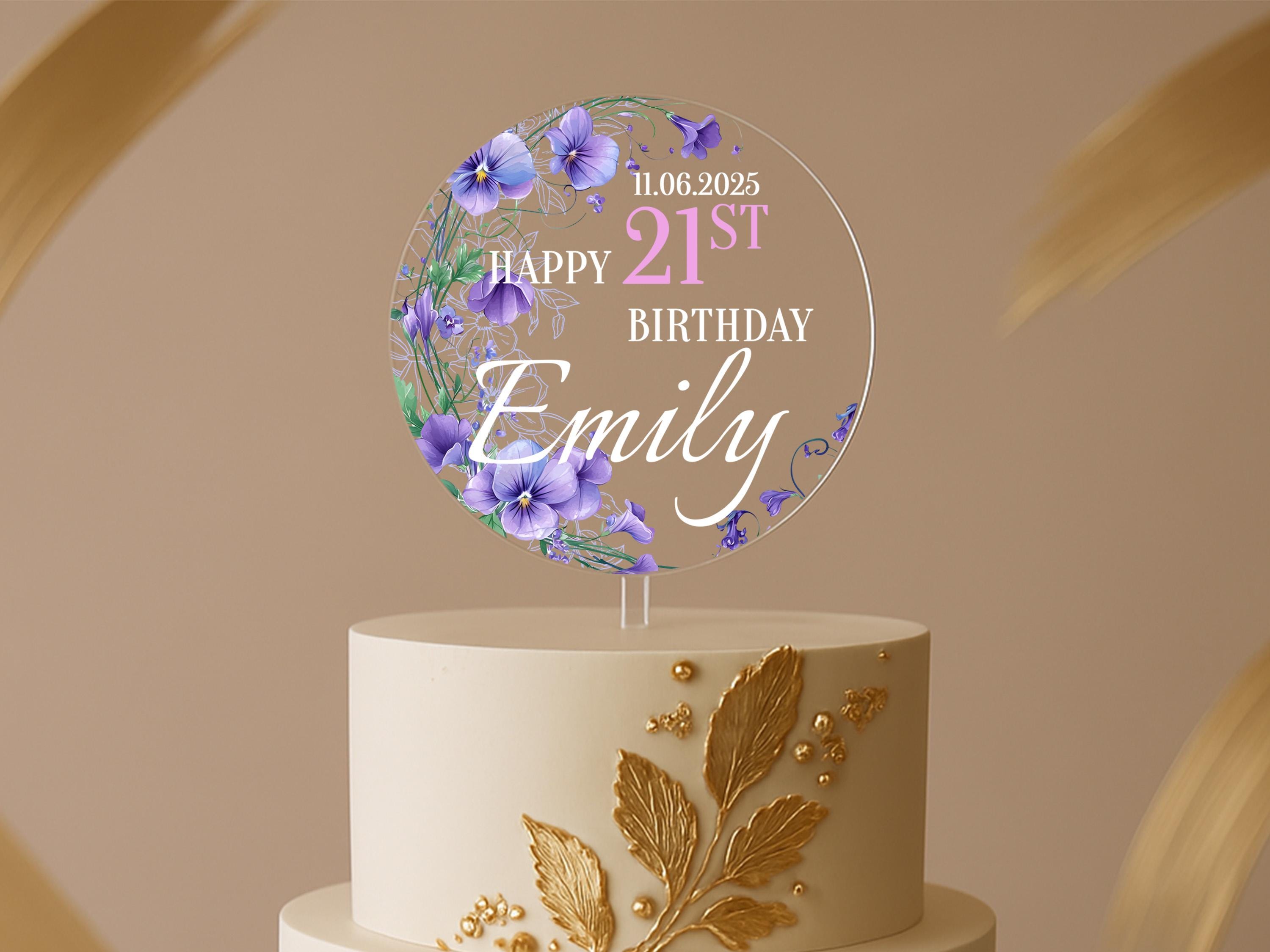 a white cake with purple flowers and a happy 21st birthday sign
