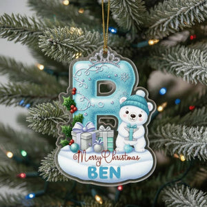 A Christmas ornament shaped like the letter "P" with a polar bear and presents, hanging on a tree.