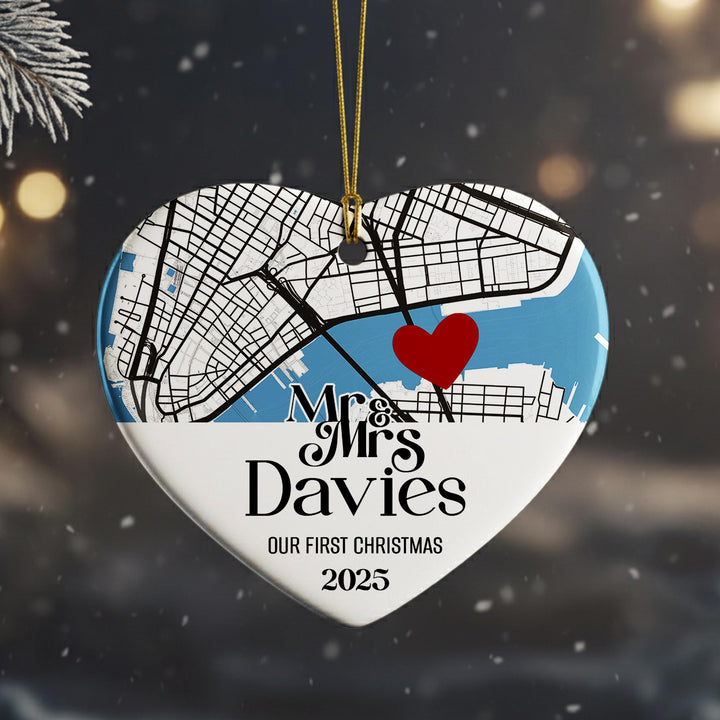 A heart-shaped ornament with a map of a city and a red heart symbol, along with the text &quot;Mr & Mrs Davies&quot; and &quot;OUR FIRST CHRISTMAS 2025&quot;.