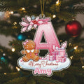 A pink glittery letter "A" ornament with a gingerbread man and presents, hanging on a Christmas tree.