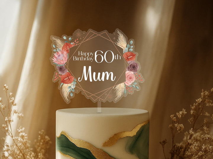 A birthday cake with a floral topper that says &quot;Happy Birthday 60th Mum&quot;.