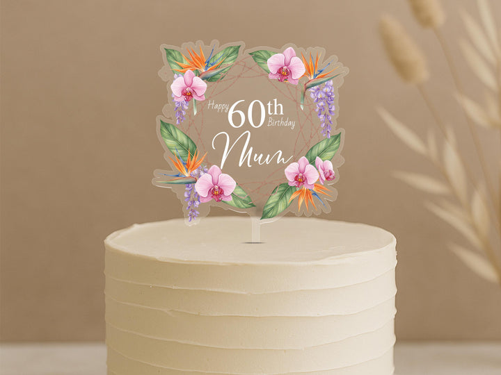 Personalised 60th birthday cake topper featuring elegant tropical floral design with orchids, bird of paradise flowers, purple wisteria and custom name Mum in square frame on white celebration cake