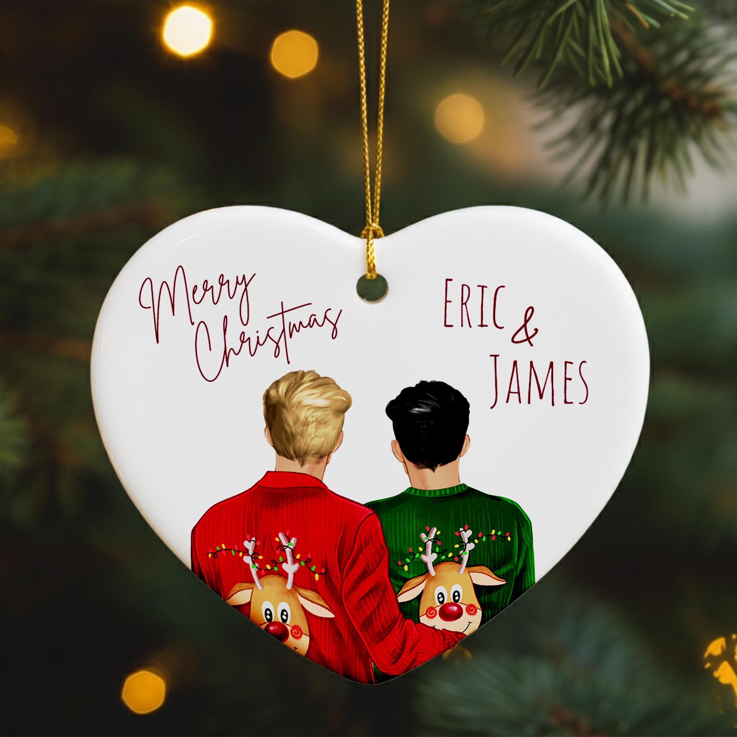 A heart-shaped ornament with two people wearing Christmas sweaters, one red and one green, with a deer on their backs. The ornament has a "Merry Christmas" message and the names "ERIC & JAMES" written on it.