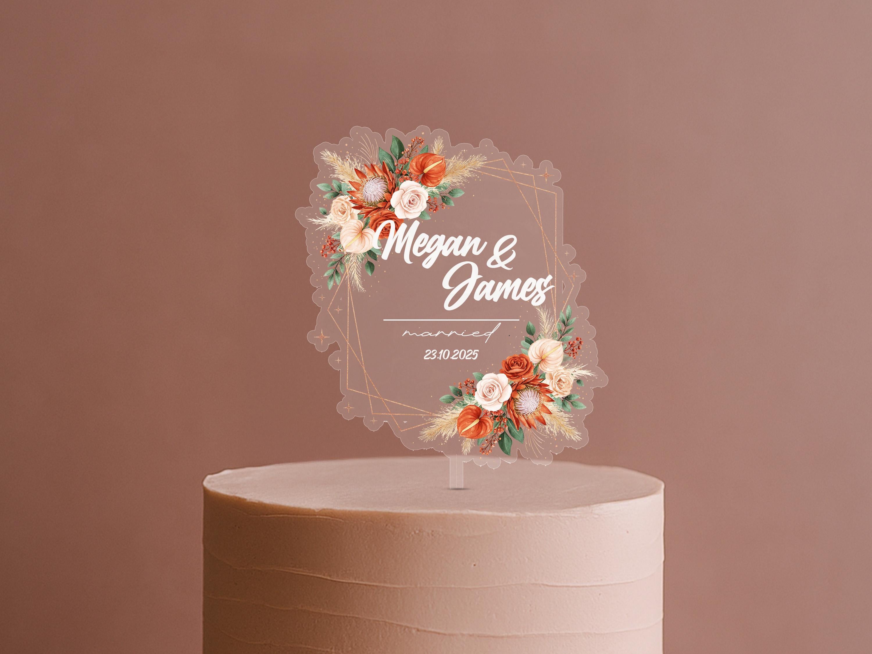 A wedding cake topper with a floral design and the names "Megan & James" written on it.