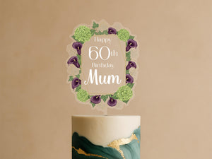 A birthday cake with a decorative topper that says "Happy 60th Birthday Mum" surrounded by a floral border.