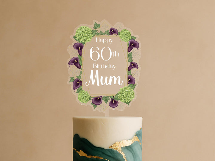 A birthday cake with a decorative topper that says &quot;Happy 60th Birthday Mum&quot; surrounded by a floral border.