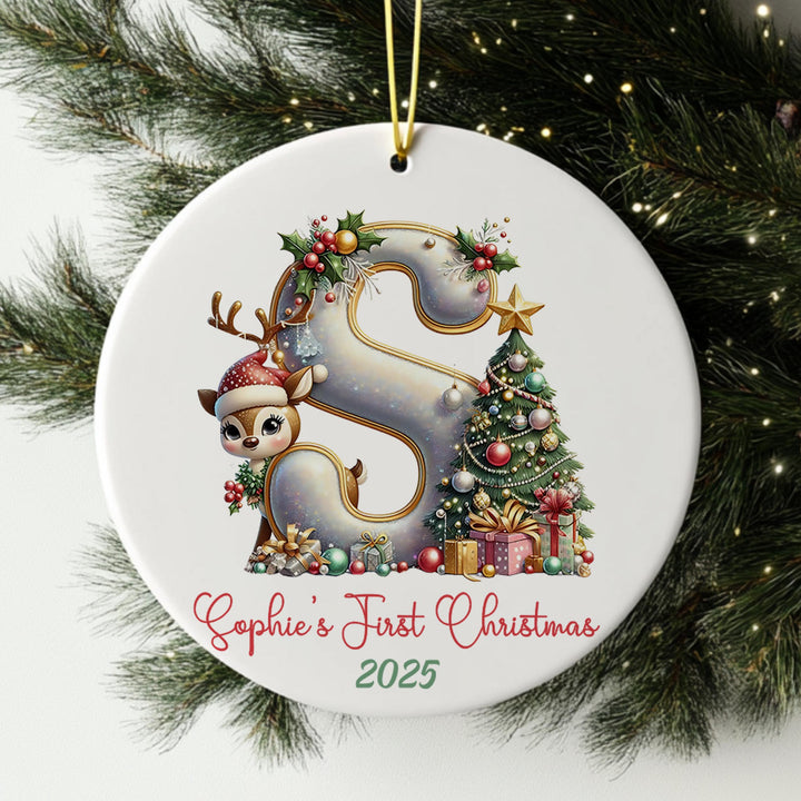 A white ornament with a decorative letter &#39;S&#39; and various Christmas-themed elements, such as a reindeer, presents, and a Christmas tree.