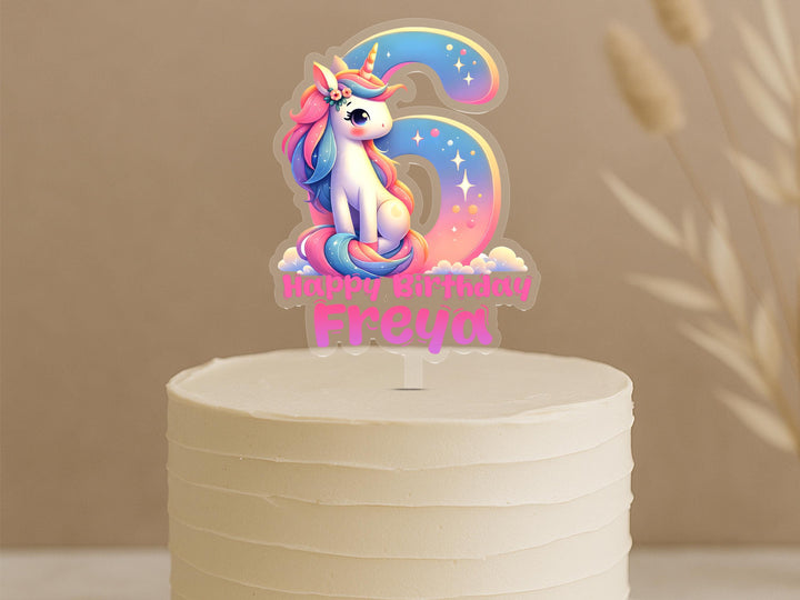 Rainbow unicorn birthday cake topper displaying number 6 with cute unicorn character and custom name Freya on buttercream cake