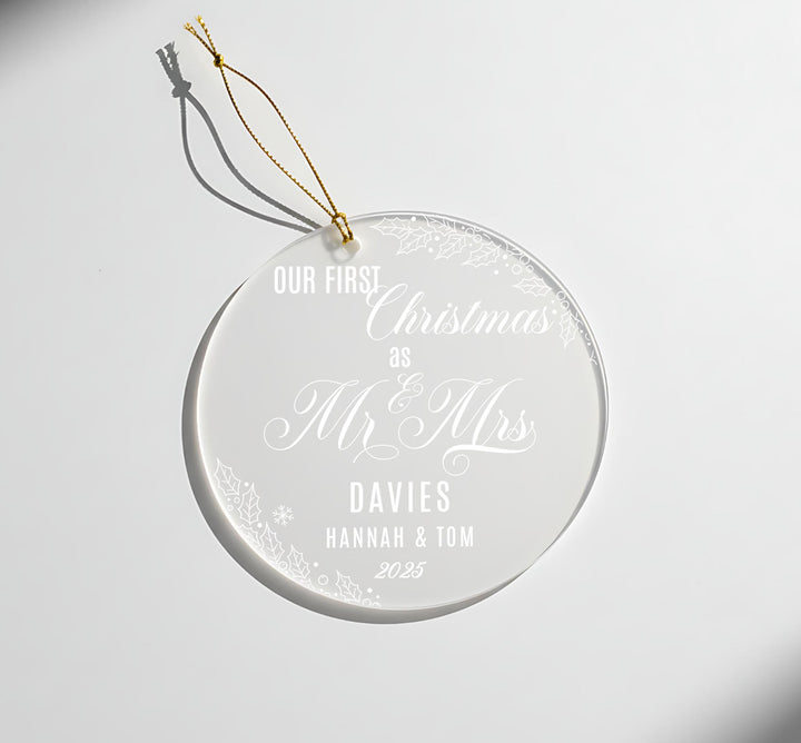 A clear ornament with a gold string attached, displaying a message about a couple.