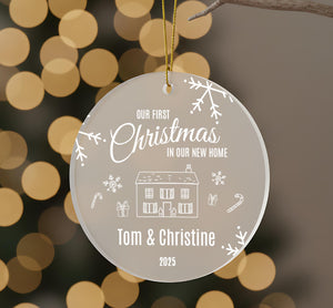 A Christmas ornament with the text "Our first Christmas in our new home" and illustrations of a house, snowflakes, and candy canes.