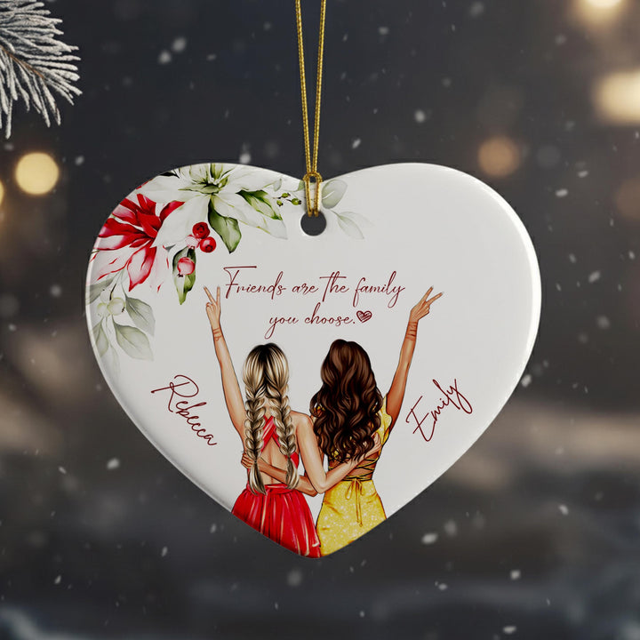 A heart-shaped ornament with two women in a loving embrace, surrounded by flowers and the text &quot;Friends are the family you choose&quot;.
