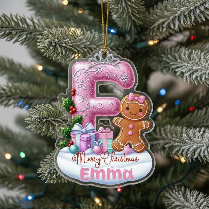 A pink ornament with a gingerbread man and presents is hanging on a Christmas tree.