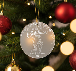 A Christmas ornament hanging on a tree, featuring a couple and the text "Our first Christmas engagement David & Emma 2015".