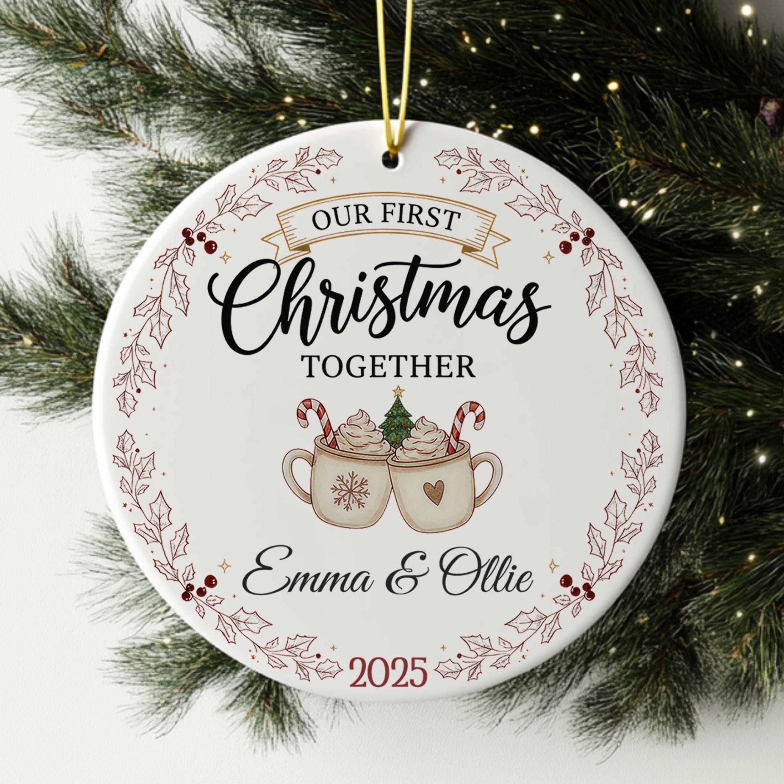 A white Christmas ornament with the text "Our first Christmas together" and an illustration of two mugs with hot chocolate and candy canes.