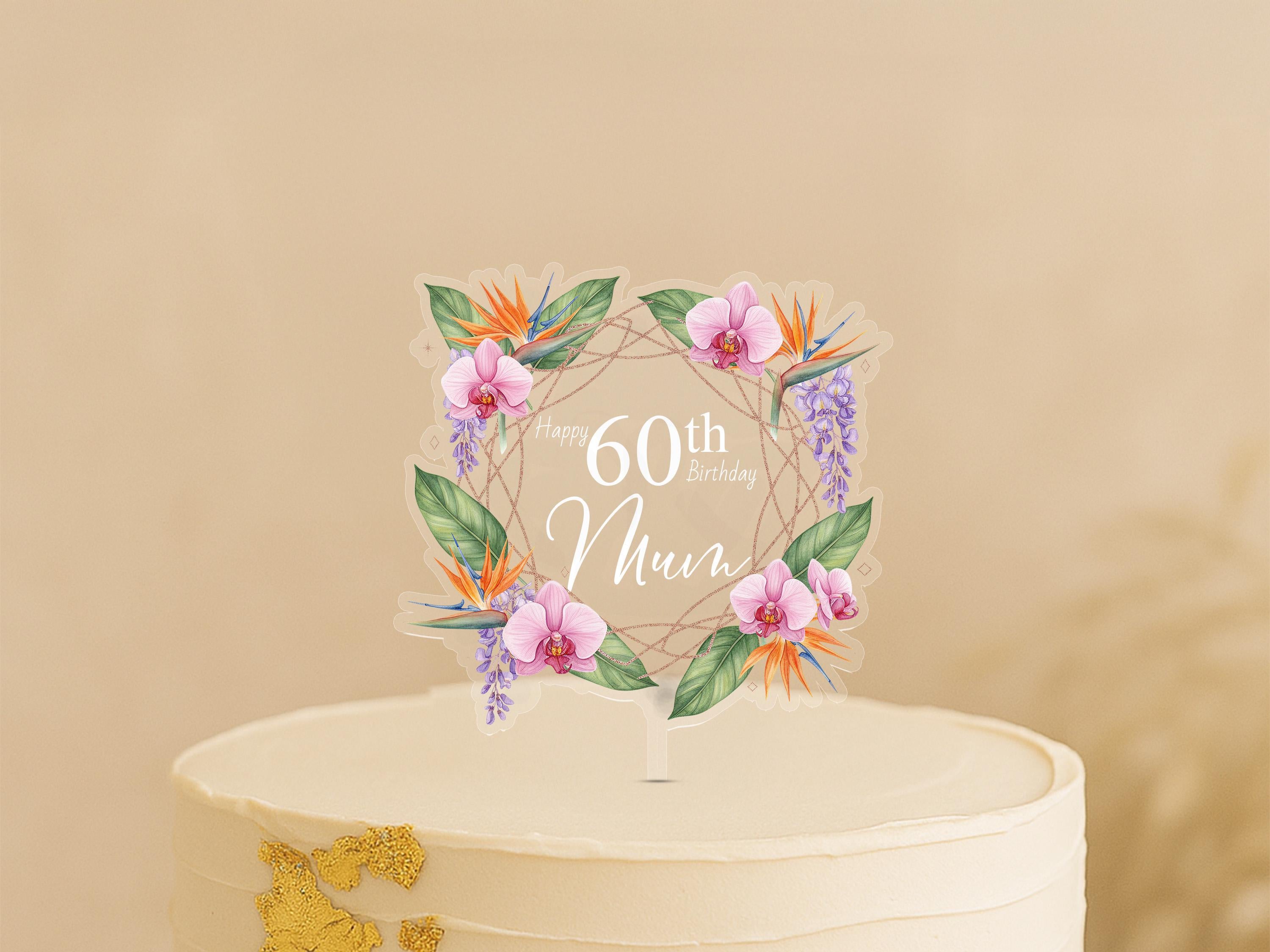 A cake topper with a wreath of flowers and the text "Happy 60th Birthday Mom" on it.